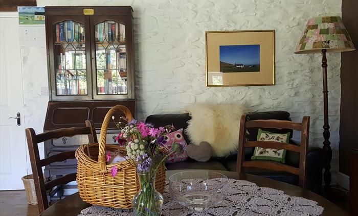 Hen Ffermdy cottage reading corner with sofa, sheepskin throw and cabinet full of books